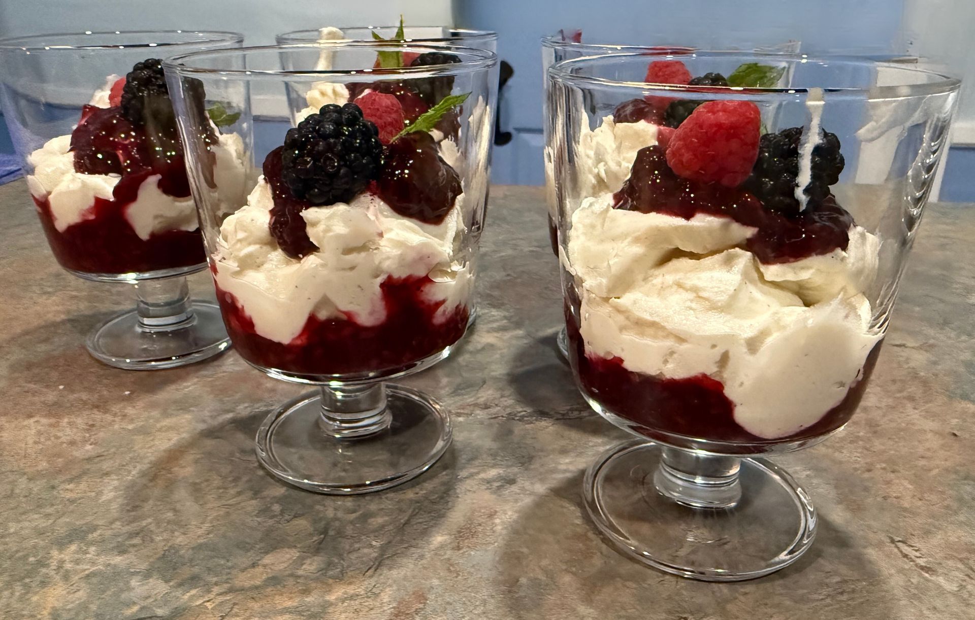 Three glasses filled with whipped cream and berries on a table