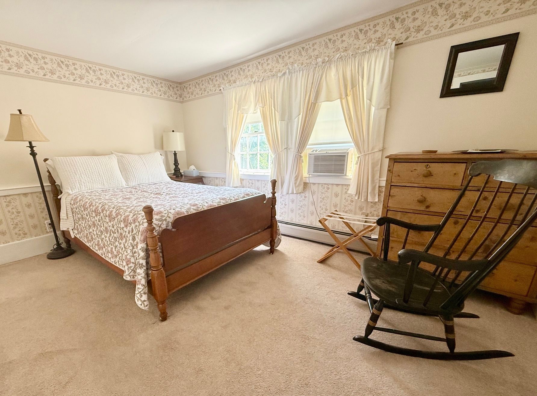 A bedroom with a bed , dresser , and rocking chair.