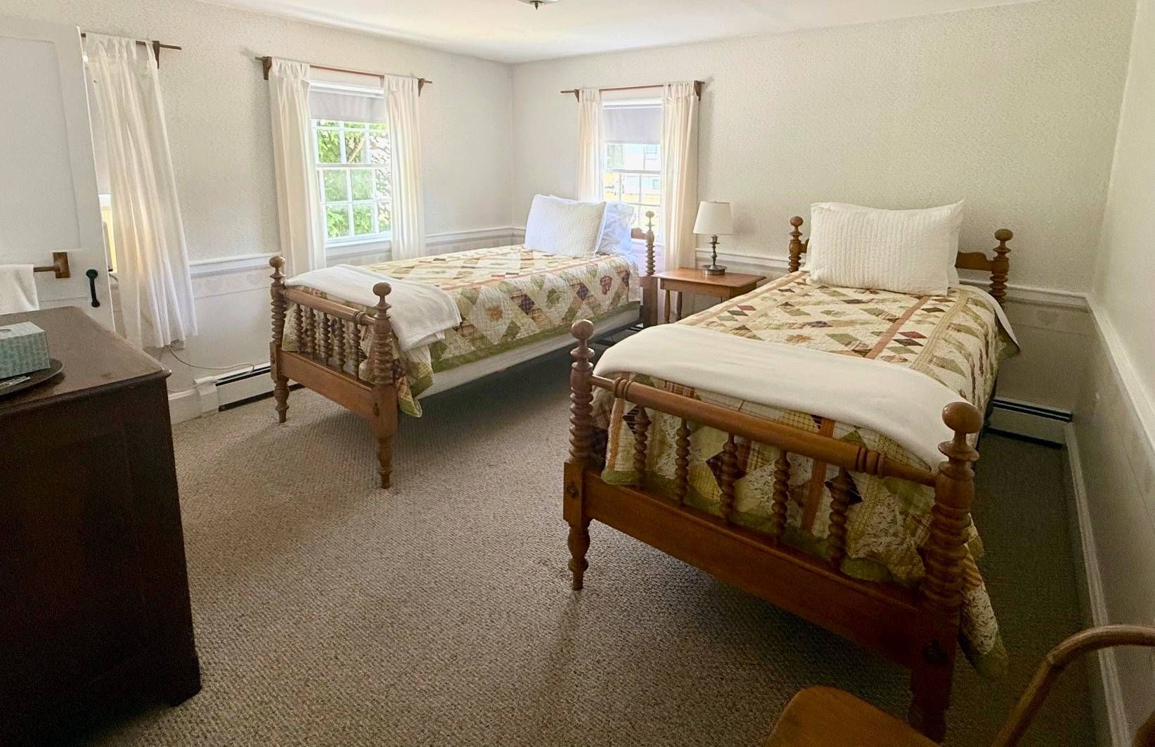 A bedroom with two twin beds and a dresser.
