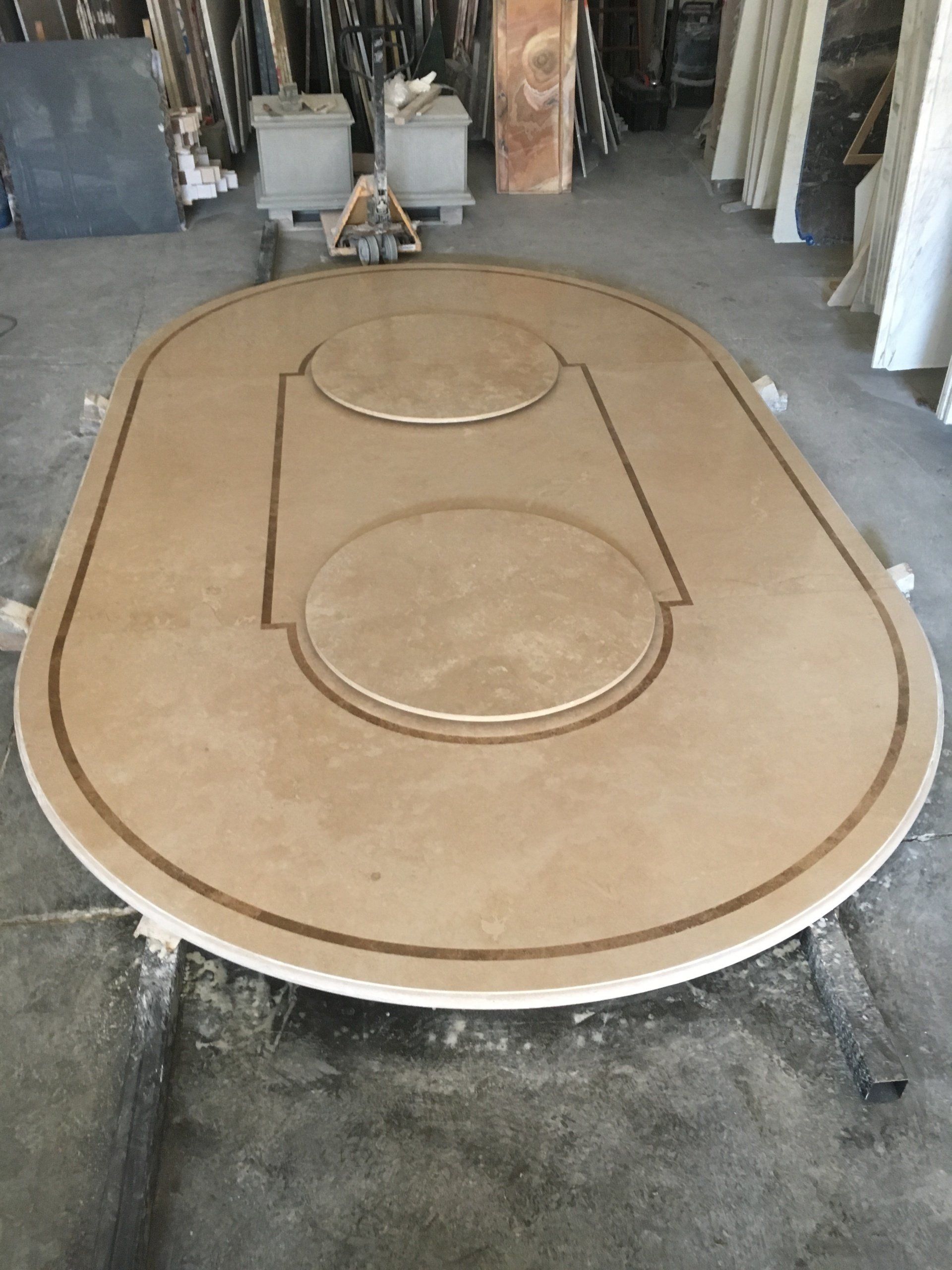 Tavolo ovale in pietra beige con due intagli circolari e un sottile bordo marrone, in un ambiente da laboratorio.