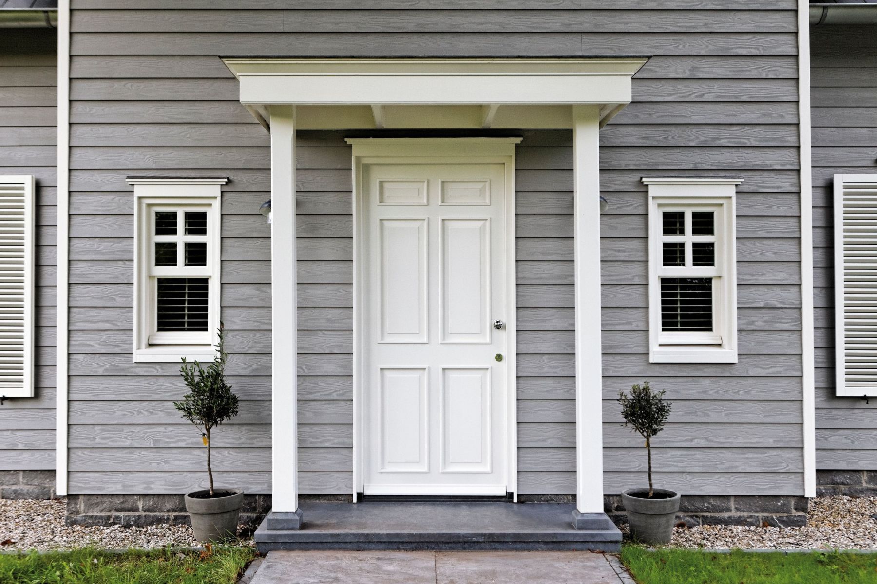 A gray house with a white door and windows