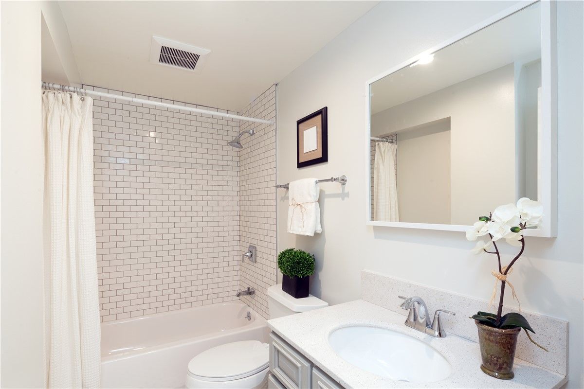 A bathroom with a toilet , sink , and mirror.