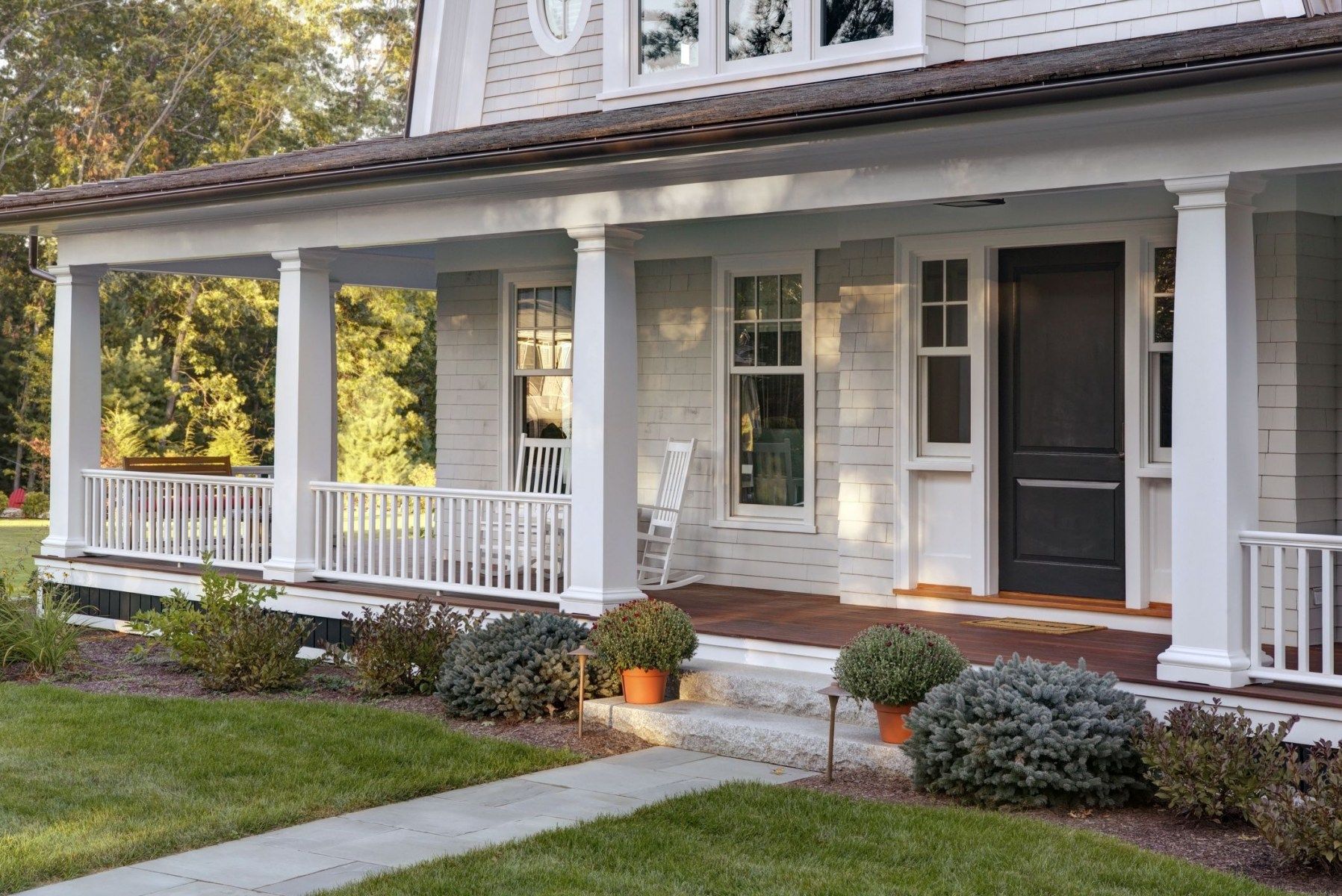 A white house with a large porch and a black door