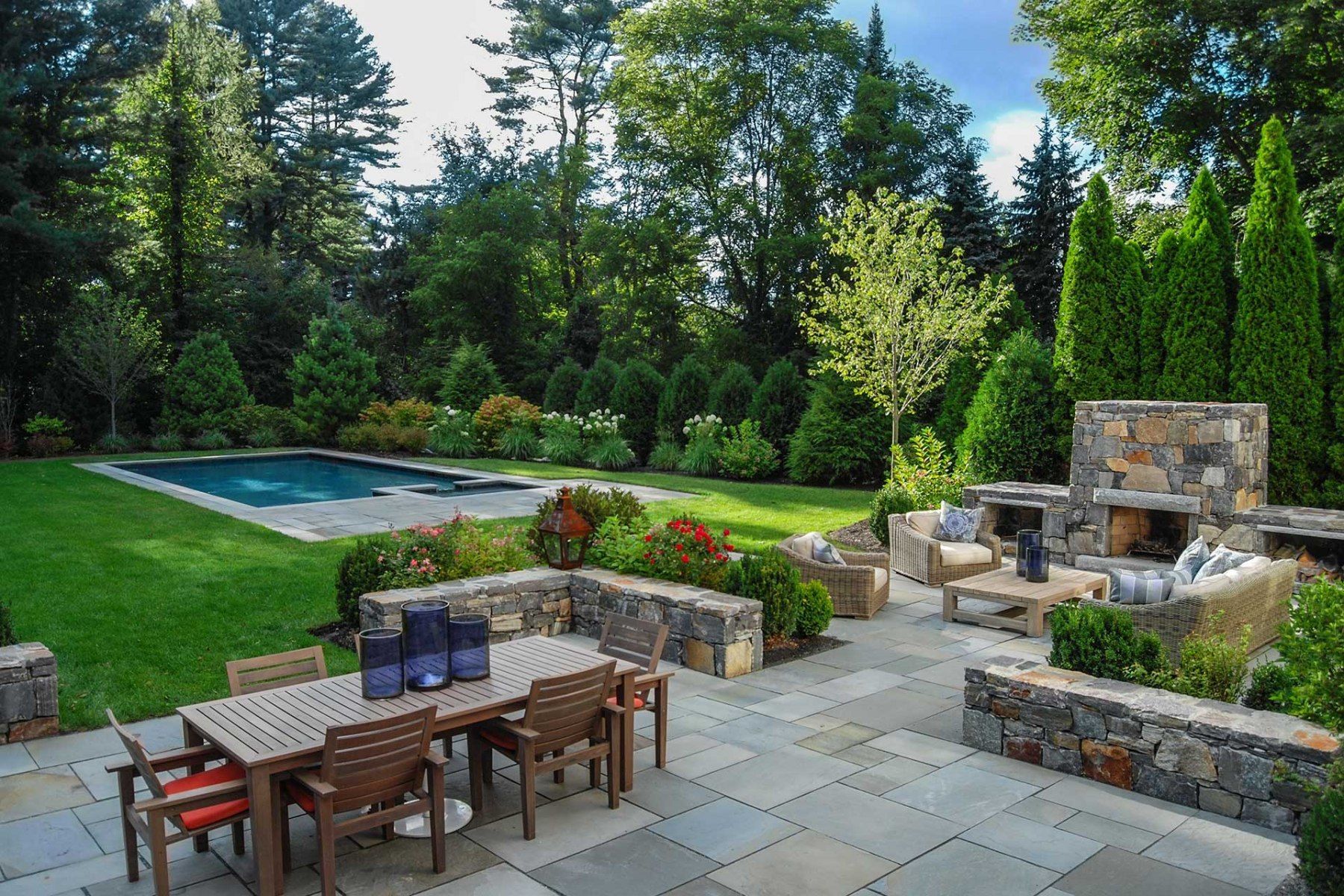 A patio with a table and chairs and a pool in the background