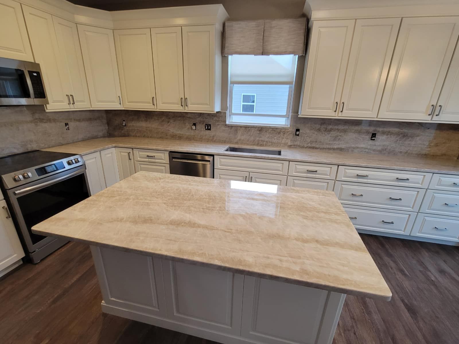 A kitchen with white cabinets and a large island in the middle.