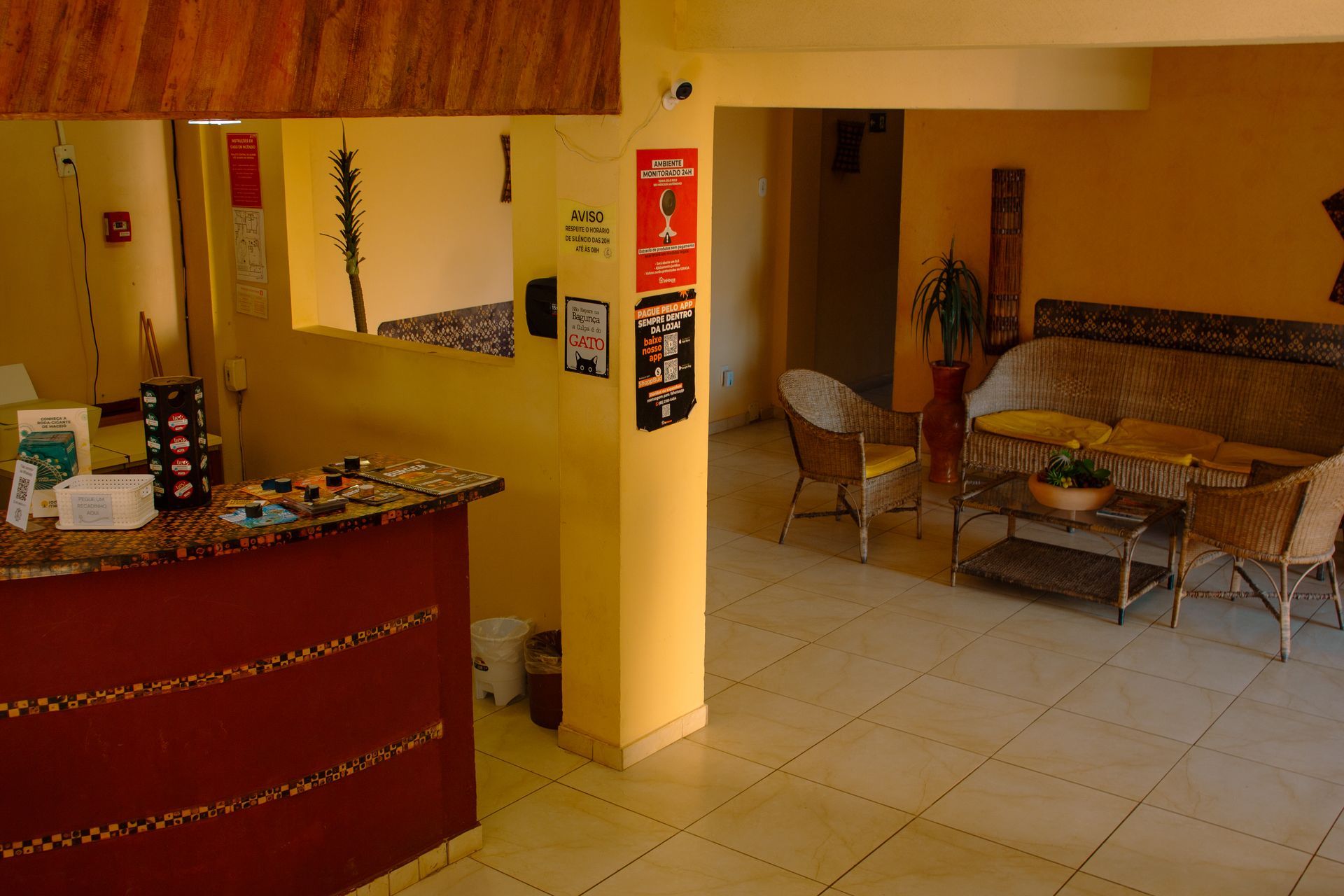 Hall de entrada com balcão vermelho, paredes bege e uma pequena área de estar com cadeiras e mesa.