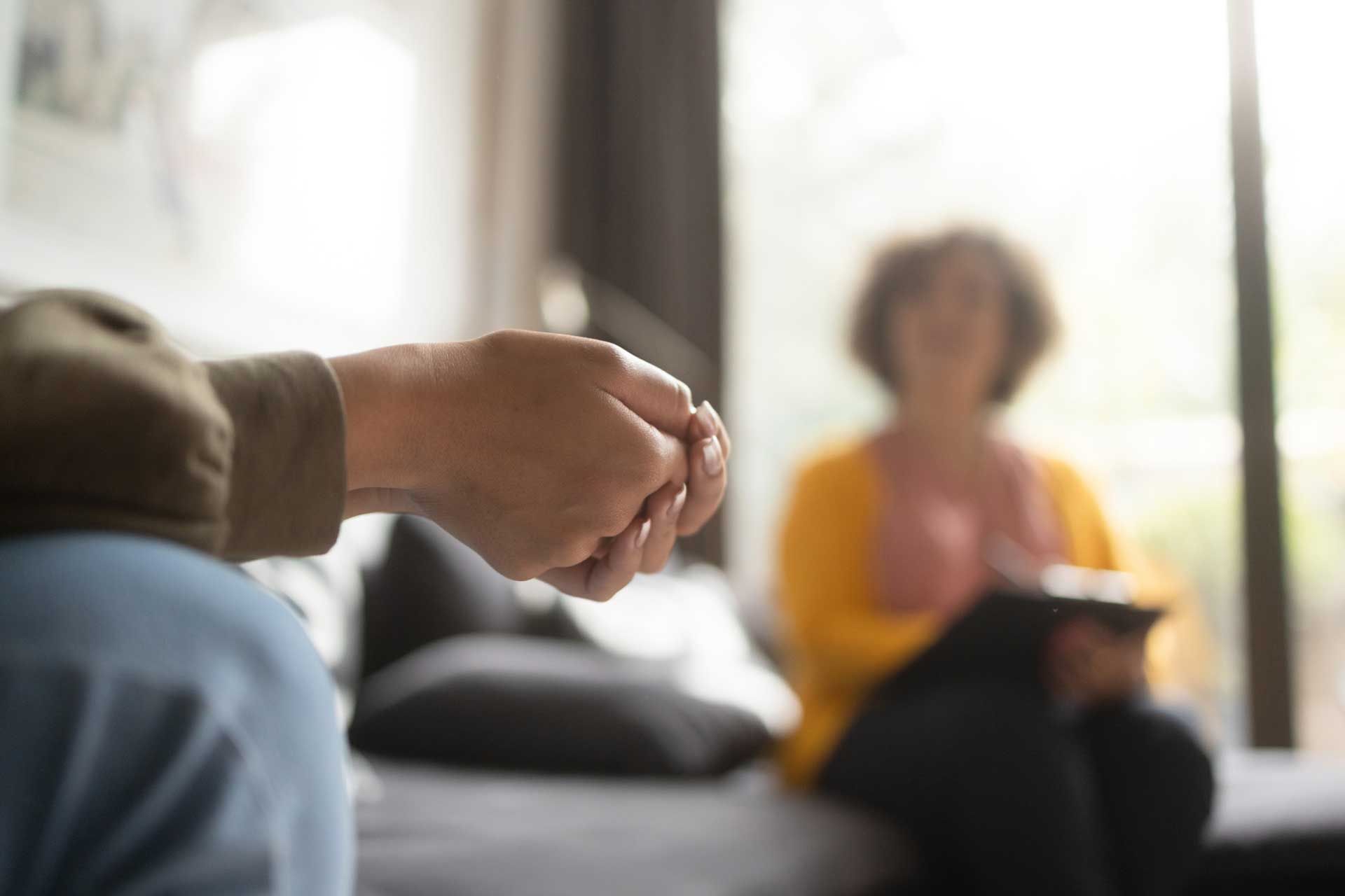 A person is holding another person 's hand while sitting on a couch.