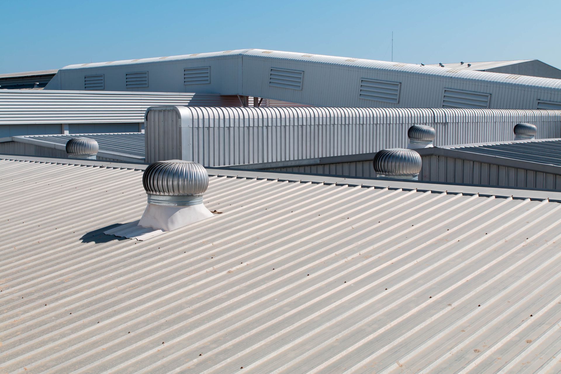 Industrial metal roof with turbine vents — commercial roofing maintained by W. C. Louis Roofing