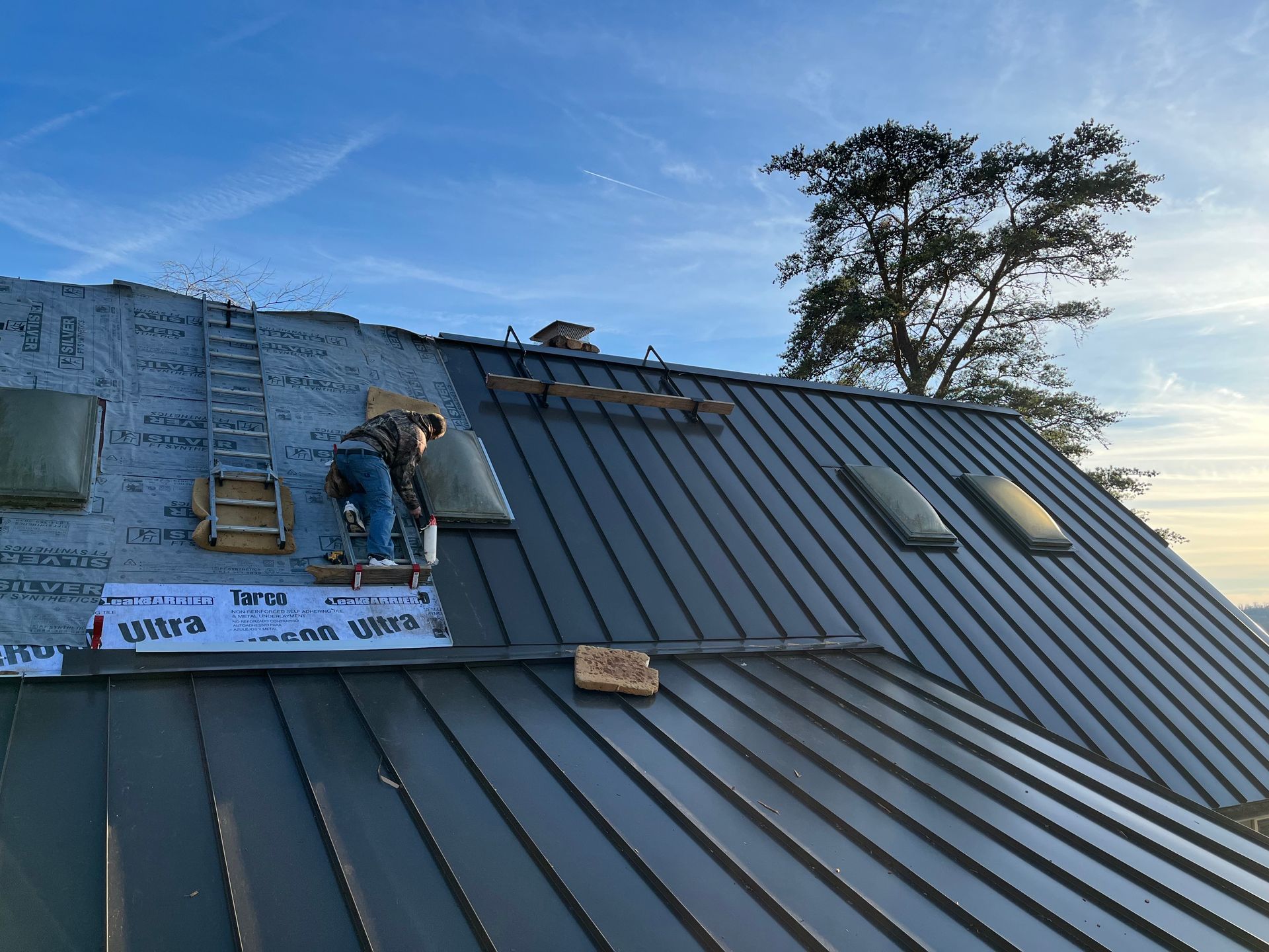 Roofer installing metal roofing panels on a Dickson, TN home — W. C. Louis Roofing