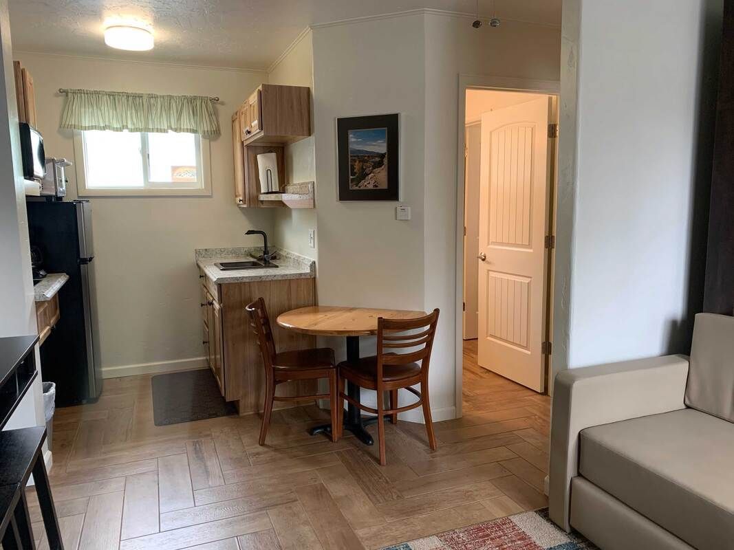 Small studio apartment with kitchen, round table, two chairs, and a couch. Doorway to the bathroom.
