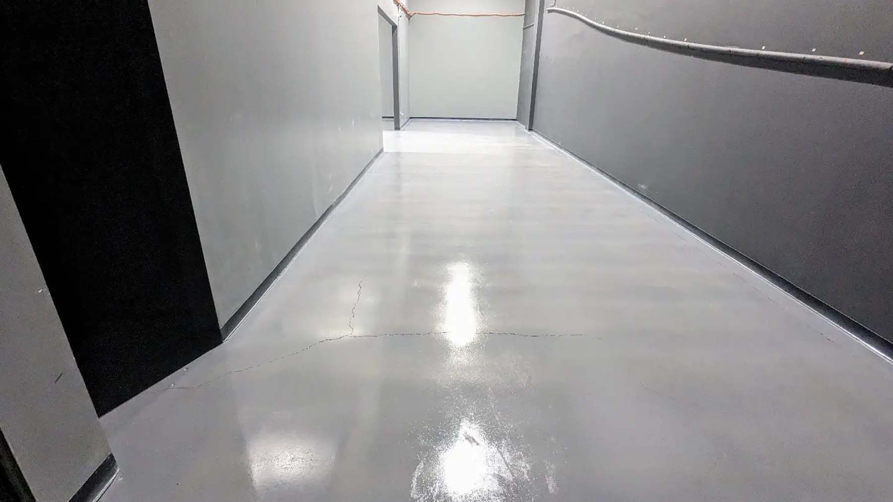 A long hallway with a white floor and a black wall.