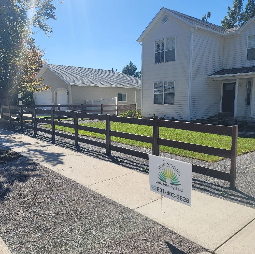 Brown wooden fence in front of a house, with a sign advertising landscaping services.