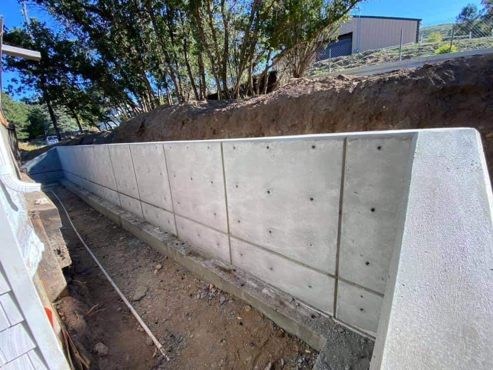 A concrete wall is being built next to a dirt road.