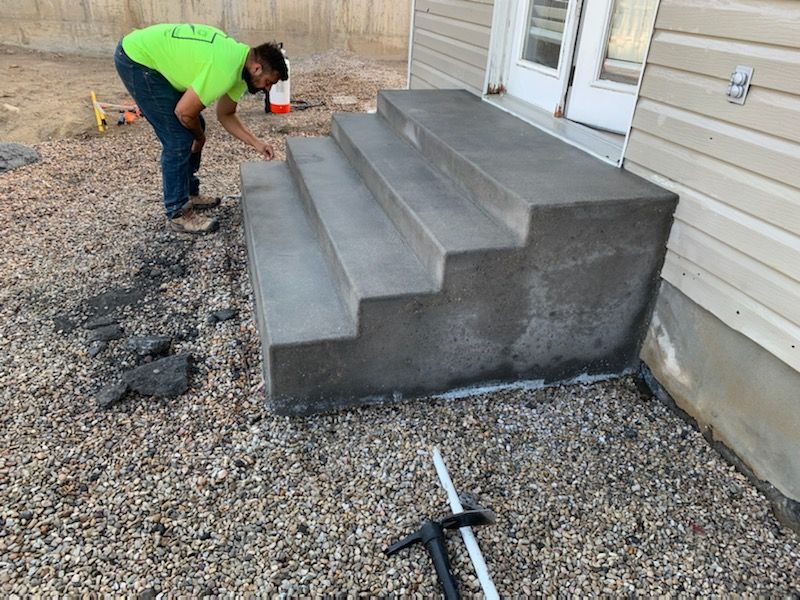 A man is working on concrete steps in front of a house.