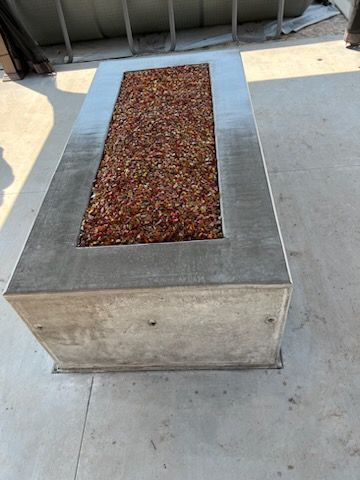 A concrete table with a fire pit in the middle of it.
