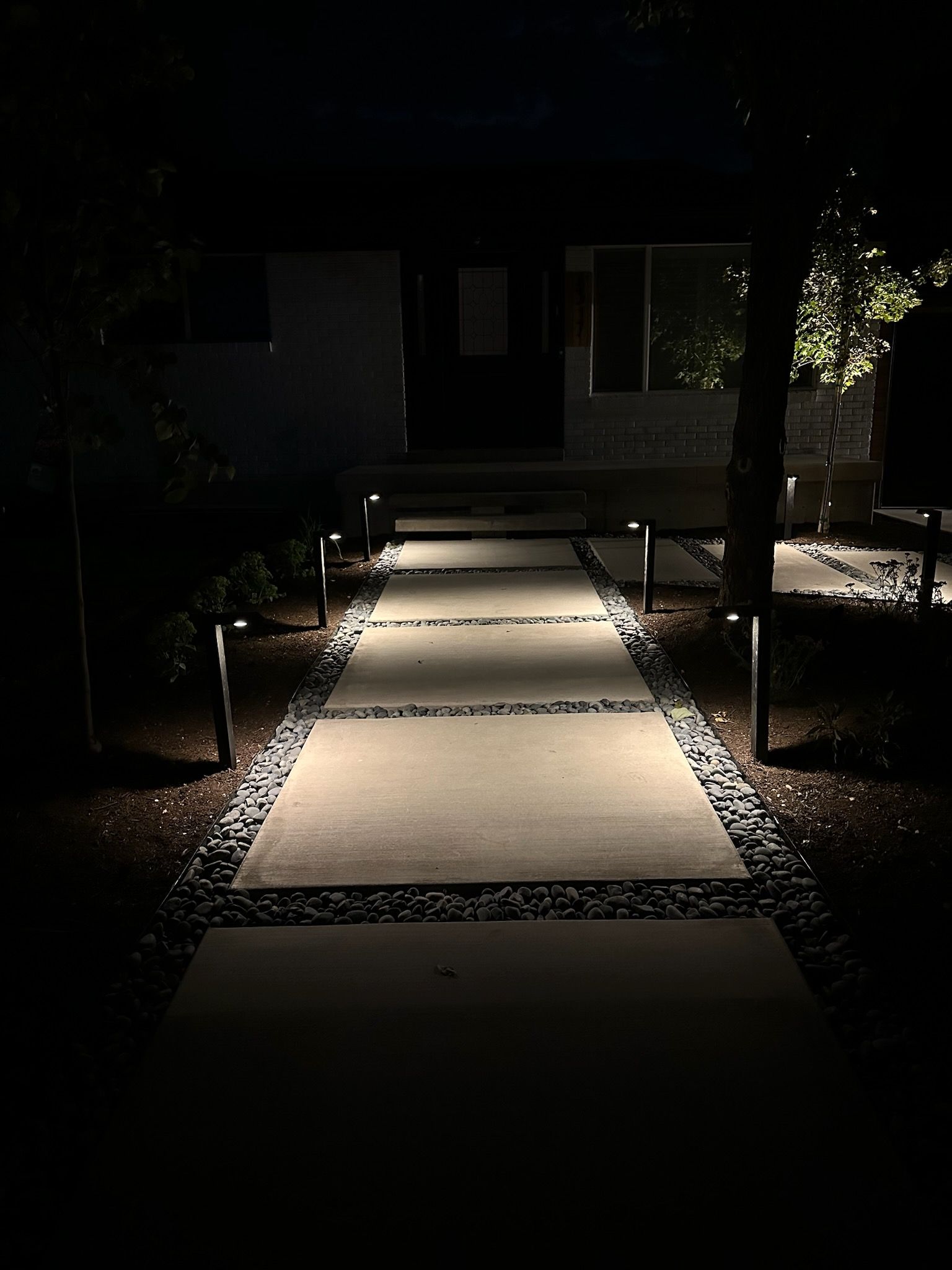 A walkway is lit up at night in front of a house.