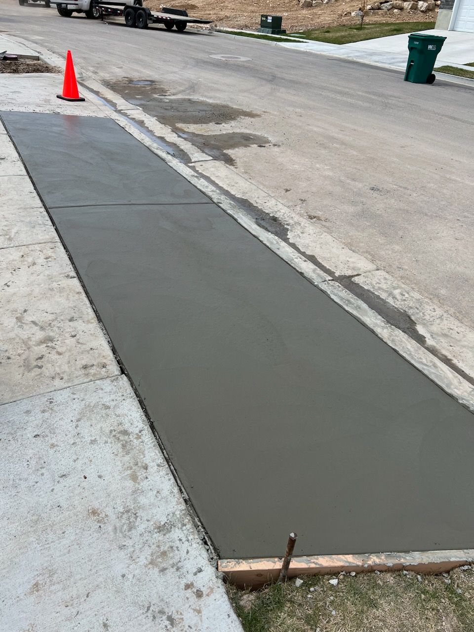 A concrete sidewalk is being built on the side of the road.