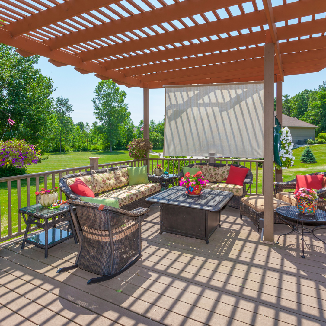 A deck with a couch and chairs under a pergola