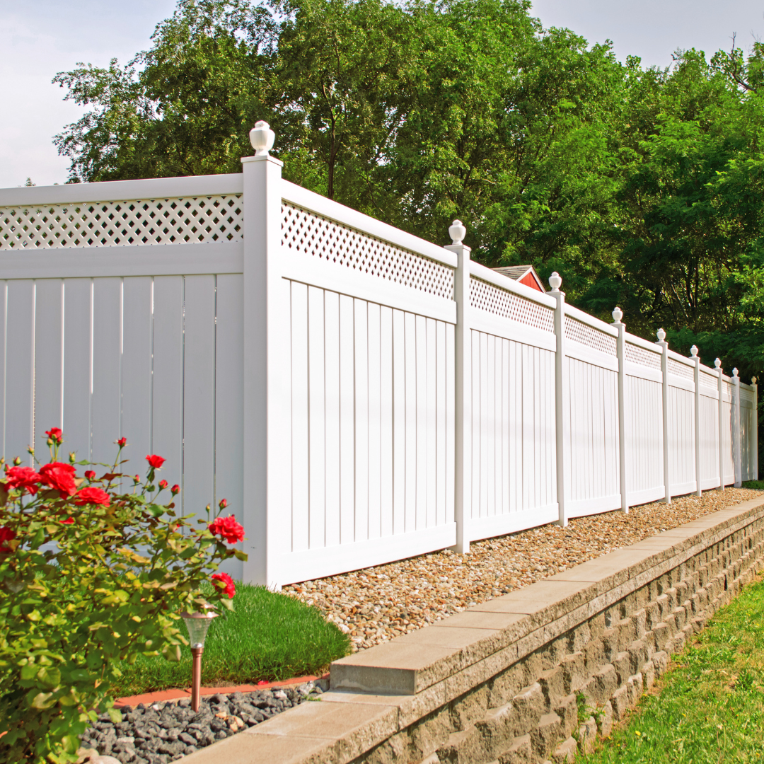 A white fence with a brick wall behind it