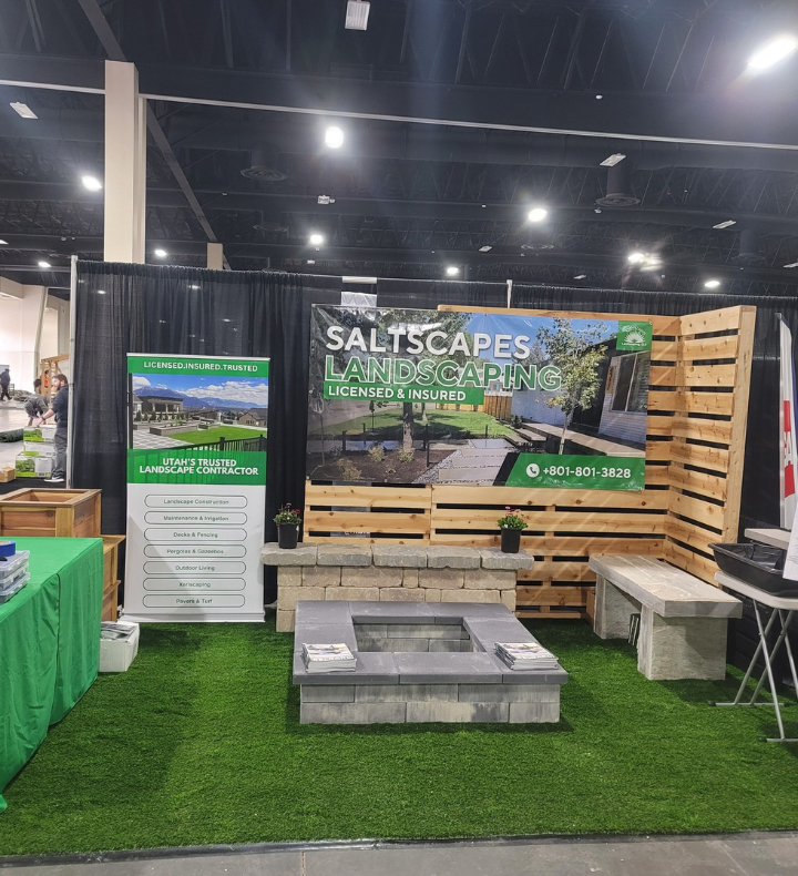 Saltscapes Landscaping trade show booth. Features a fire pit, bench, and green turf on display.