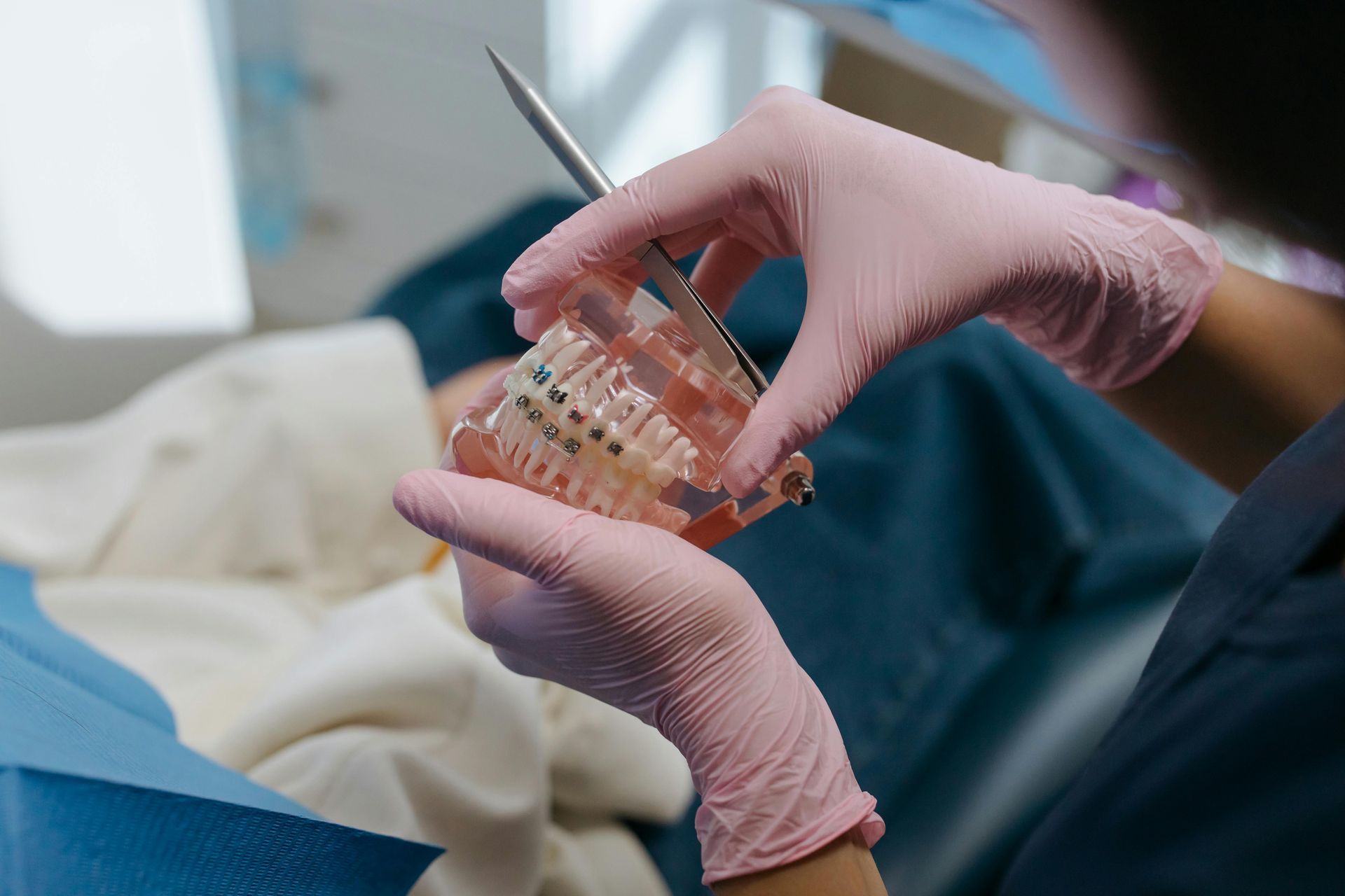 Dentist holding a model of teeth with braces, showing how they work and how to keep them clean