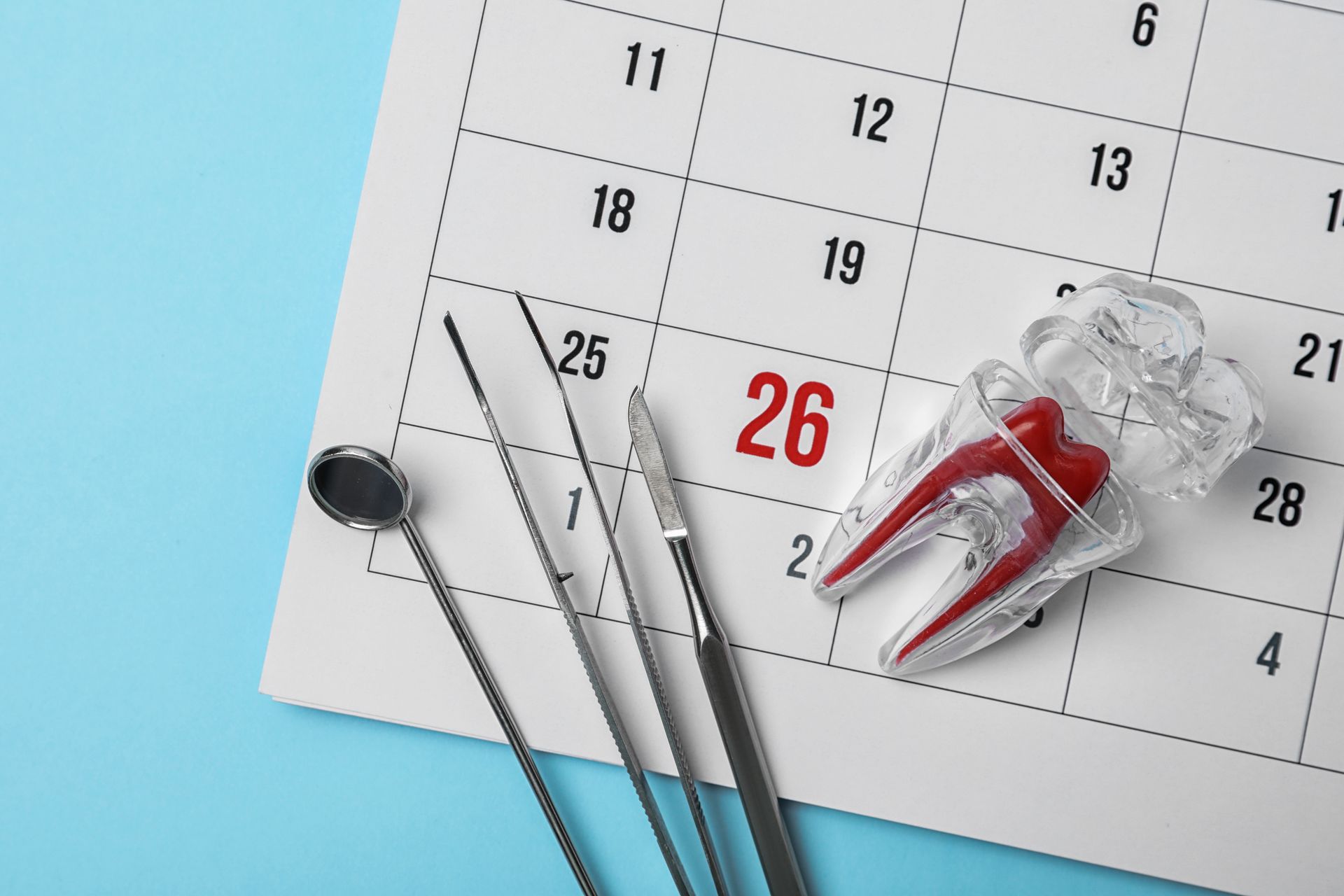 Dental tools beside a calendar marked 26, with a red-and-white tooth model