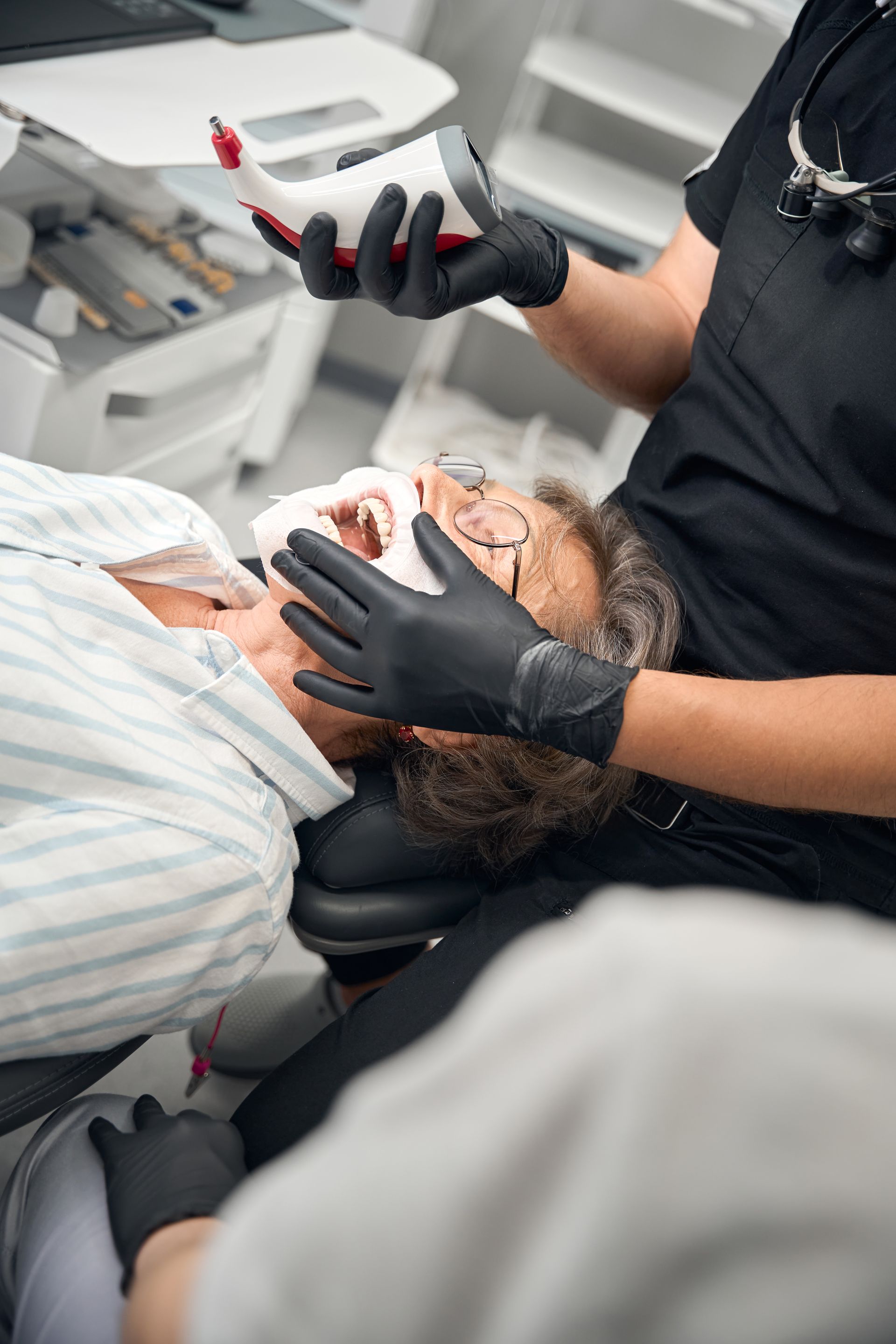 Medical professional using a tablet while examining a patient in a dental chair