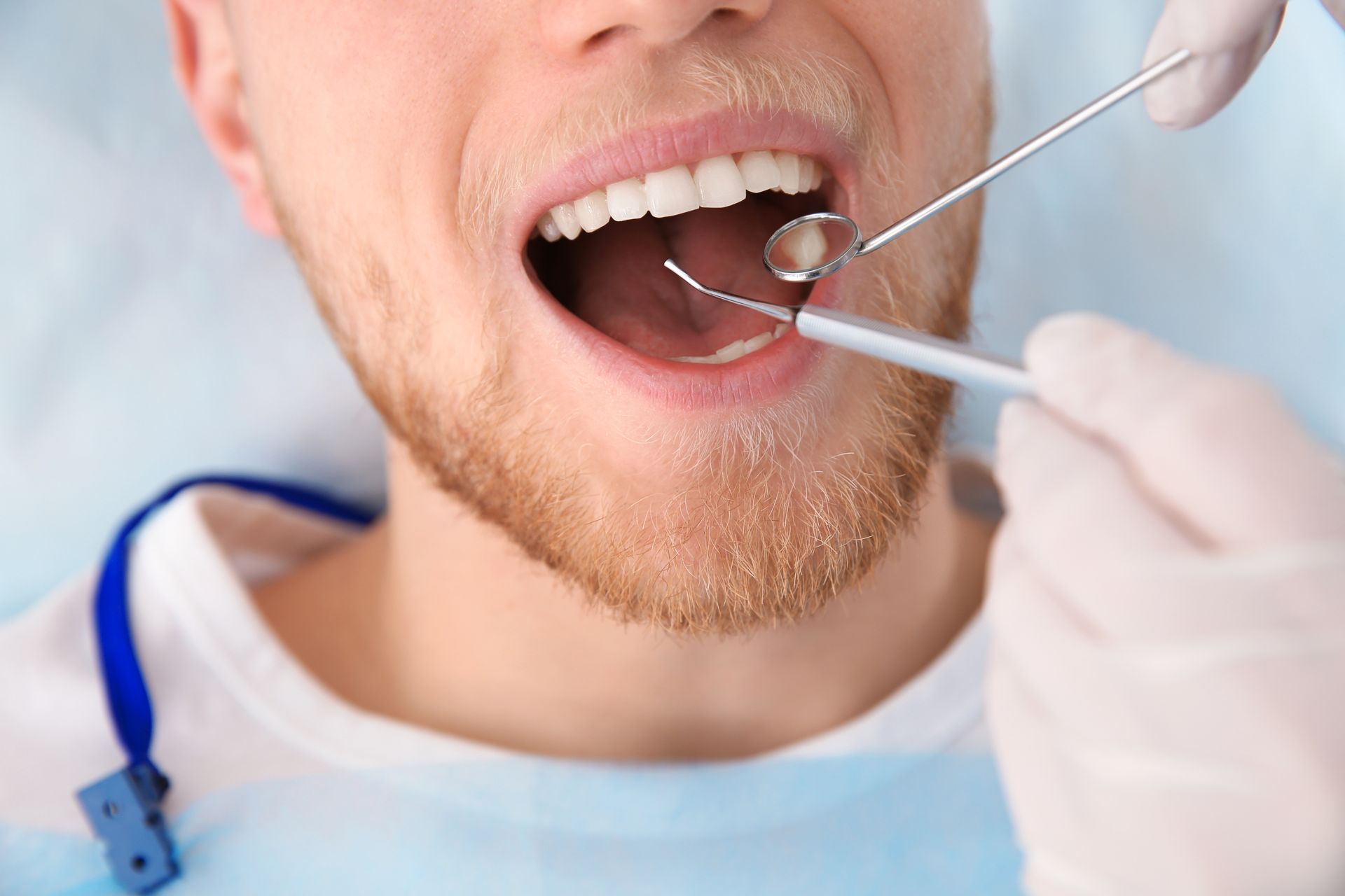 Dentist examining a patient’s open mouth with dental mirror and probe