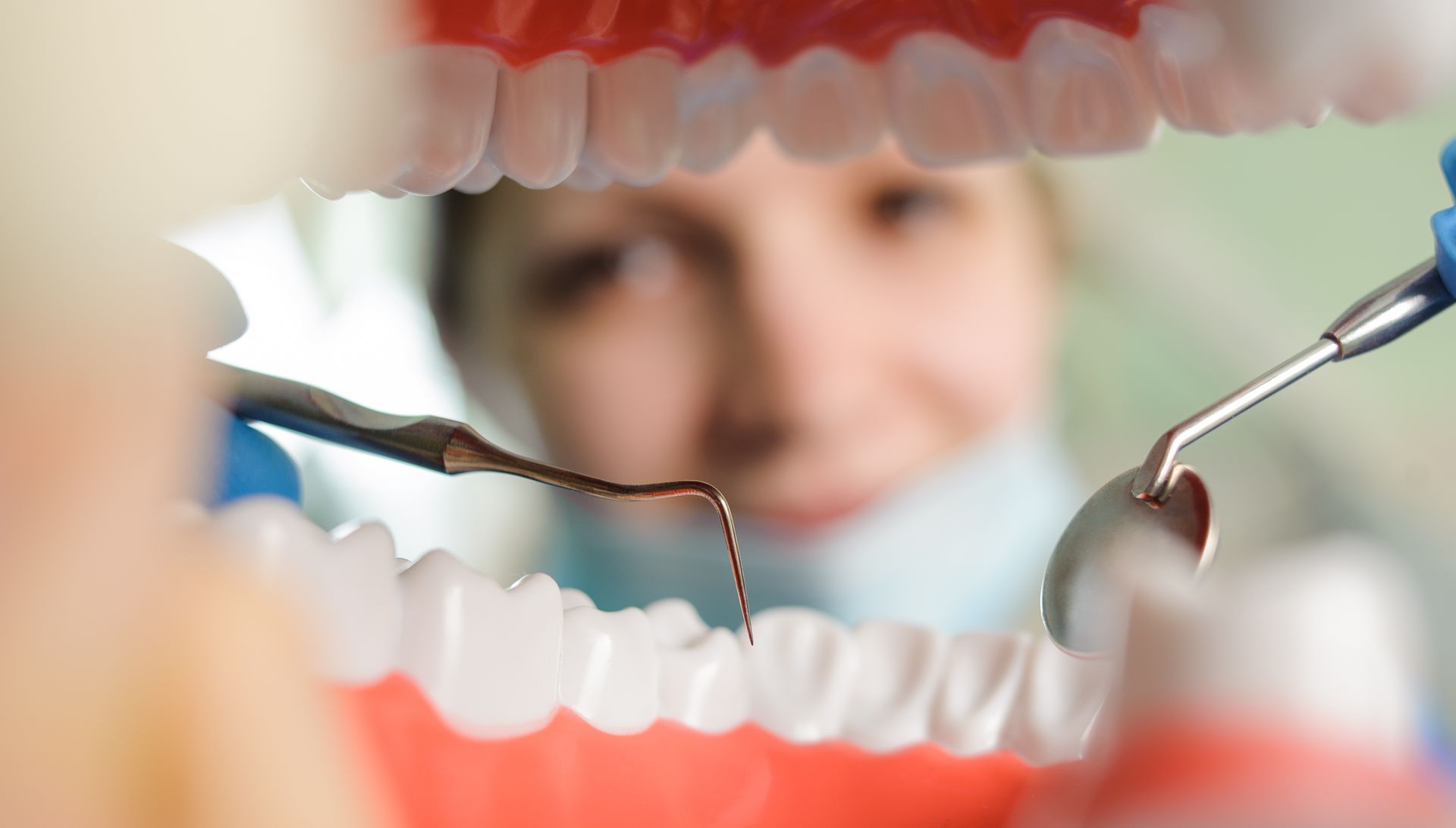 Dentist examining teeth with dental tools, viewed through an open mouth