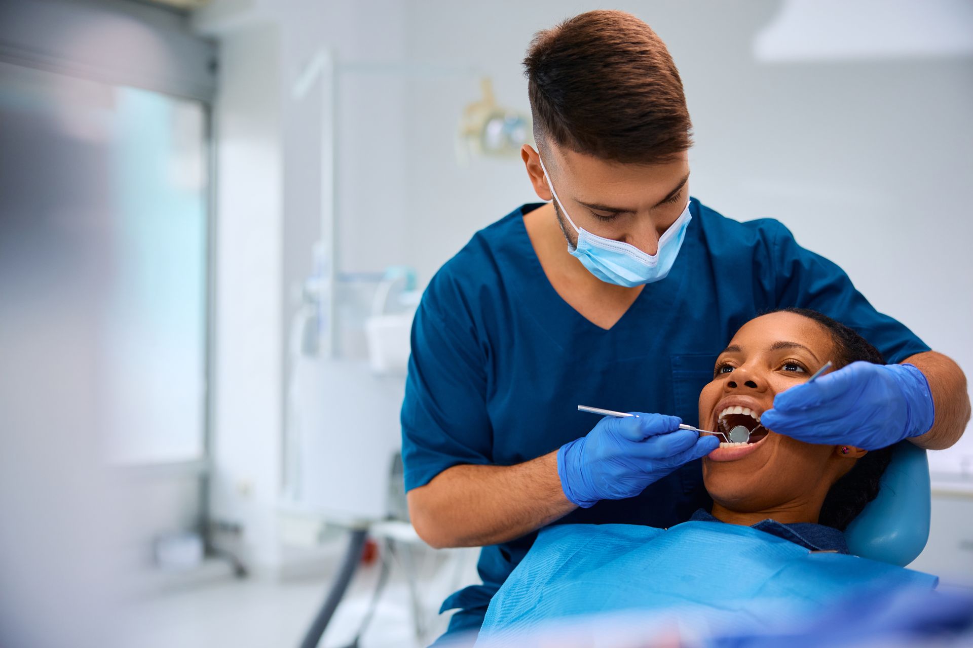 Dentist in blue gloves examining a patient in a dental clinic