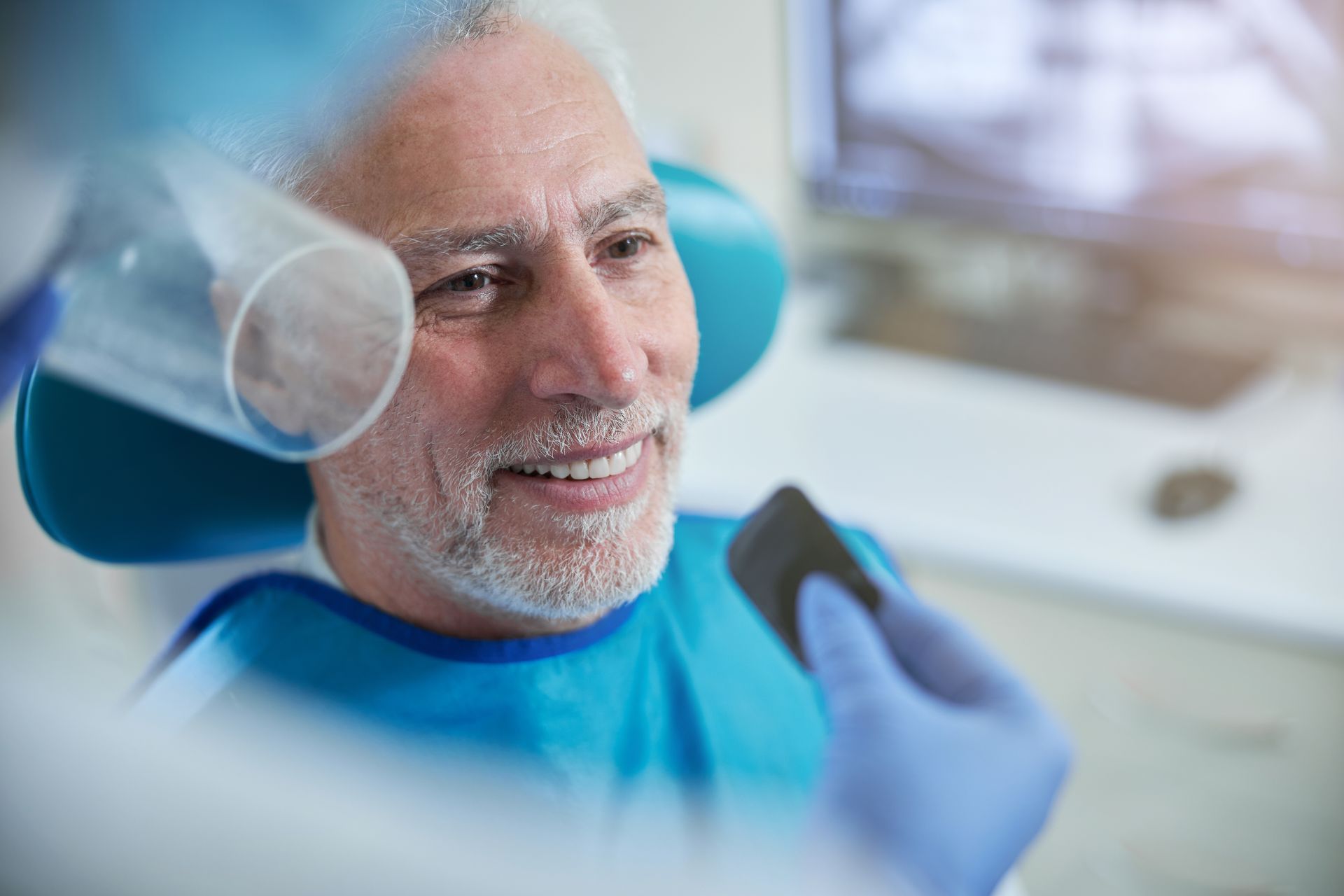 Dental model with four implants held by a gloved clinician in a lab setting