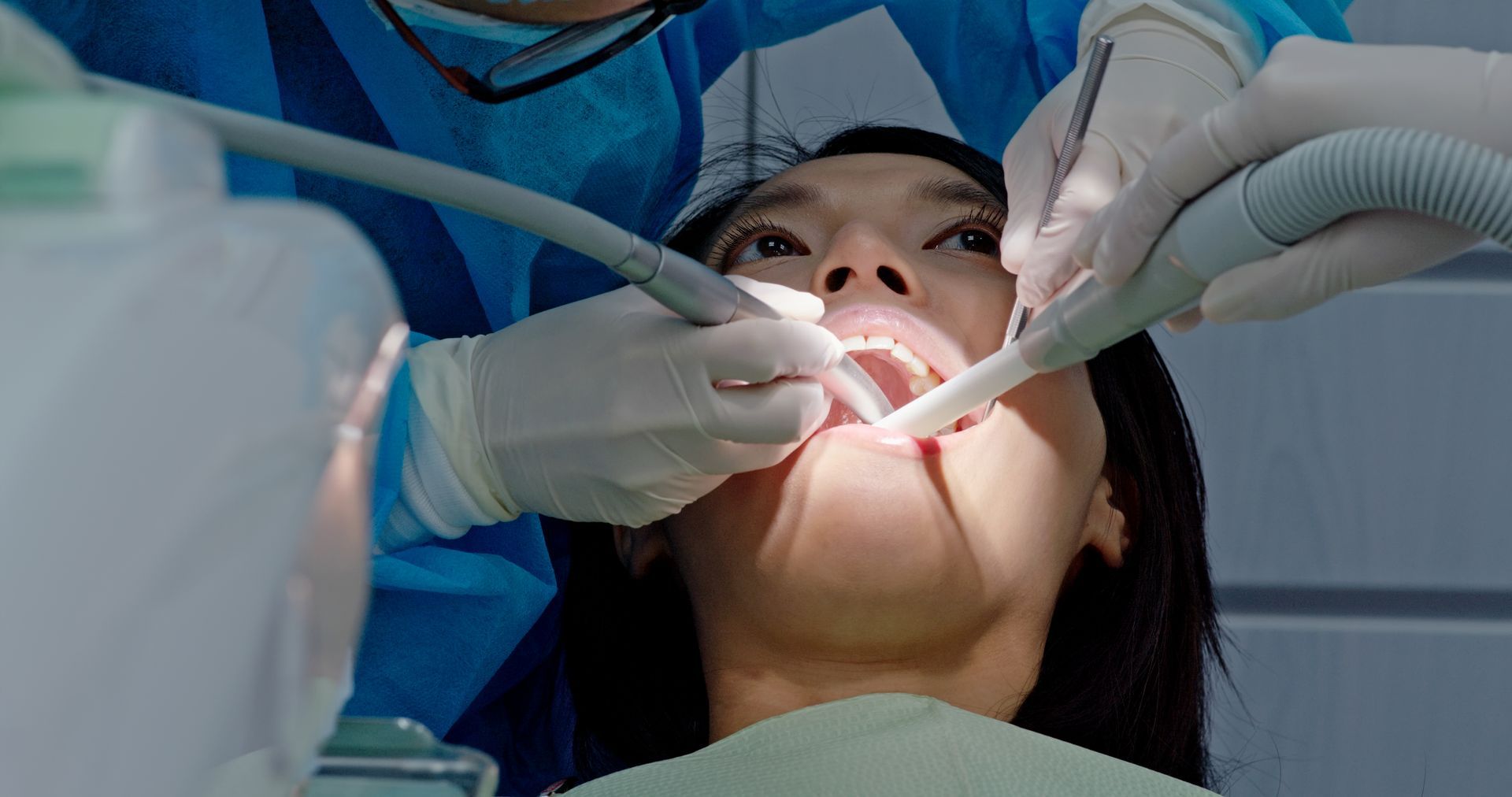 Dentist working on a patient’s open mouth with dental tools and suction