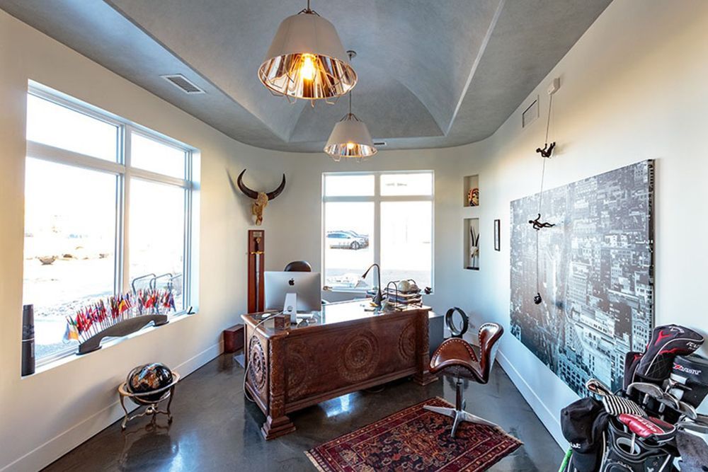 A room with a desk and chairs and a painting on the wall