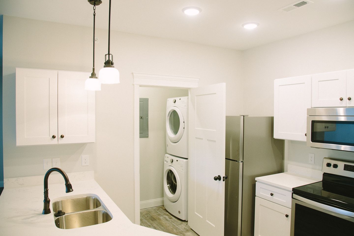 Photo of a kitchen with the laundry area seen in the background