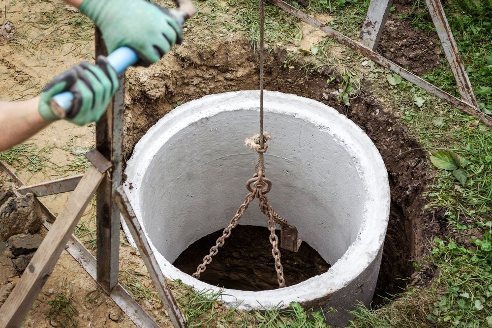 A man is lifting a concrete well with a crane.