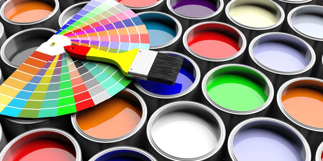 Barattoli di vernice aperti con un campionario di colori a ventaglio che mostra molte tonalità brillanti