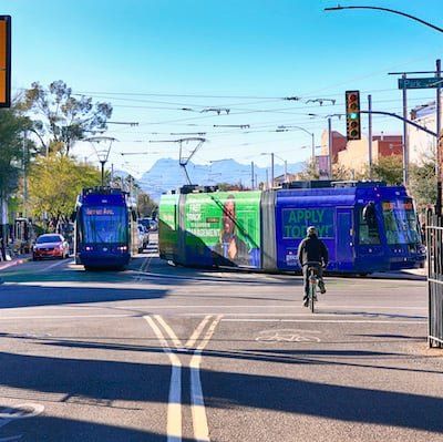 a man is riding a bike in front of a bus that says apply today.