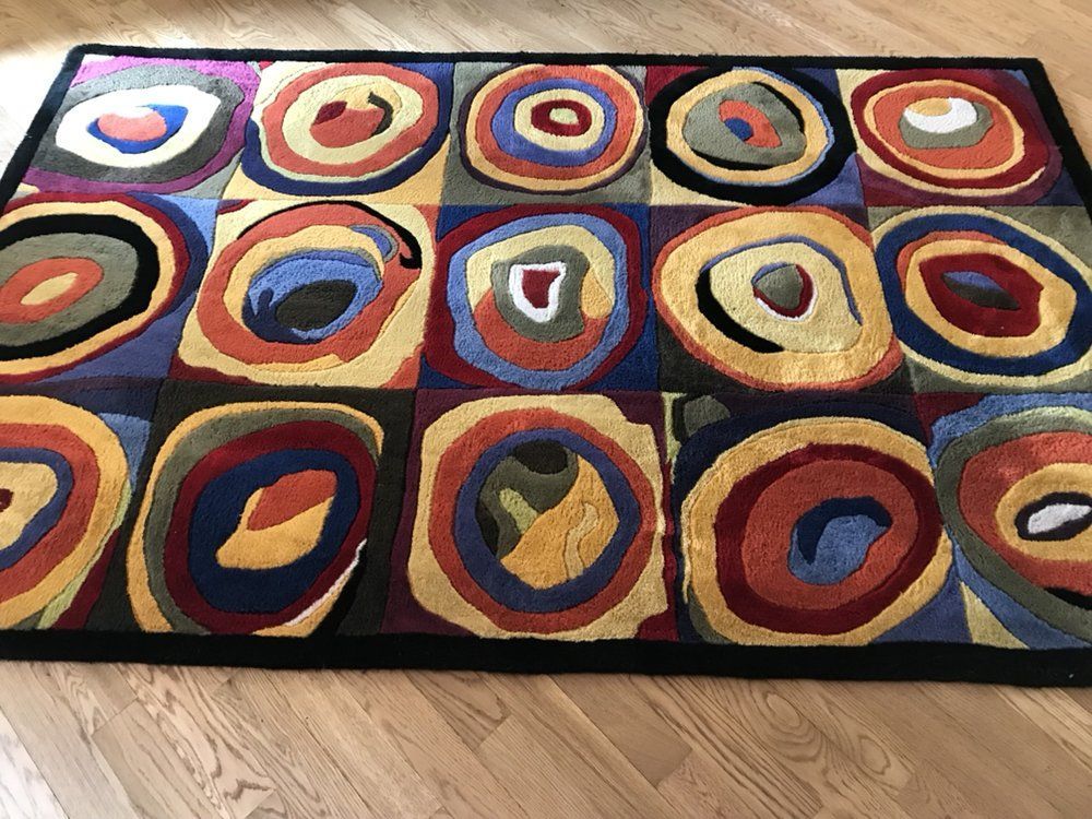 Colorful abstract rug with concentric circles and geometric shapes on a hardwood floor