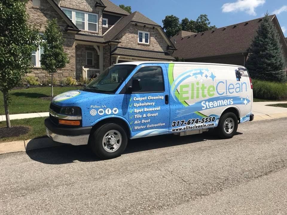Blue EliteClean Steamers van parked on a suburban street in front of a house.