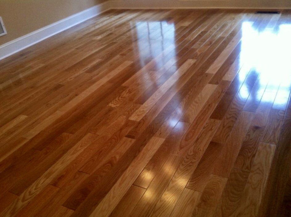 Shiny hardwood floor in an empty room with warm light reflections.
