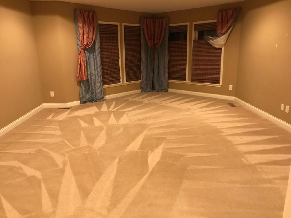 Empty beige carpeted room with corner windows, blinds, and curtains