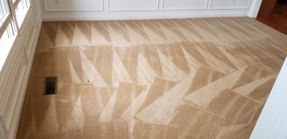 Empty room with a light wood herringbone floor and a floor vent near the wall.