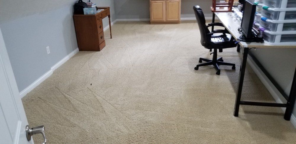 Carpeted home office with desks, chairs, and storage cabinets along the walls