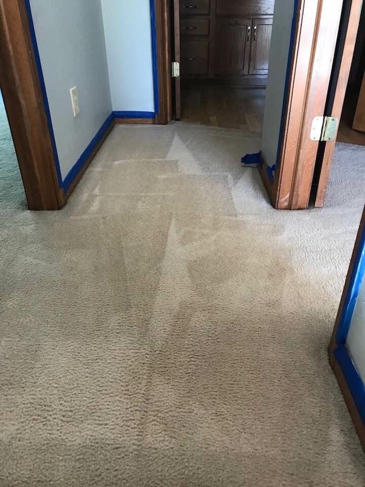 Narrow hallway with beige carpet, white walls, and wood trim leading to a closed door