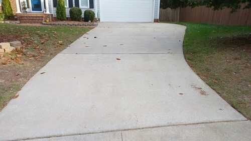 A concrete driveway leading to a house with a white garage door.
