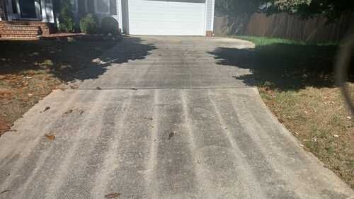 A concrete driveway leading to a garage in front of a house.