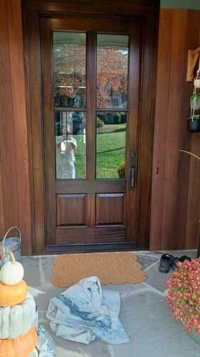 A wooden door with a door mat and pumpkins on the porch.