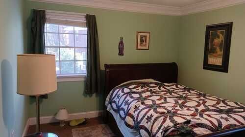 A bedroom with a bed , lamp , and window.