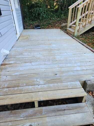A wooden deck with stairs leading up to it next to a house.