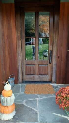 There are pumpkins stacked on top of each other on the porch of a house.